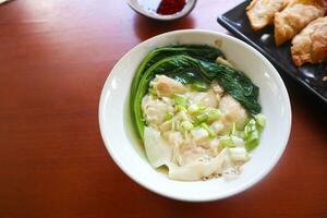 wonton soup. Bowl of wonton soup with chili oil. Shrimp or meat dumpling soup with mustard , green onions, photo