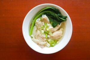 wonton soup. Bowl of wonton soup with chili oil. Shrimp or meat dumpling soup with mustard , green onions, photo