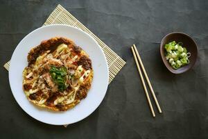 okonomiyaki, Traditional Japanese Pizza, Japanese hot plate pizza from Okonomiyaki. made of flour which is diluted with water or dashi, plus cabbage, chicken eggs, seafood and fried in a teppan photo