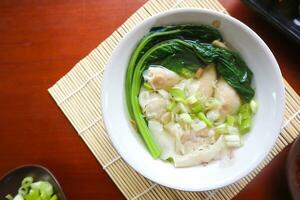 wonton soup. Bowl of wonton soup with chili oil. Shrimp or meat dumpling soup with mustard , green onions, photo