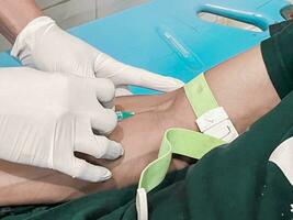 A male nurse is injecting a pain reliever anesthetic into a patient's hand photo