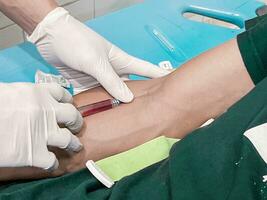 A male nurse is injecting a pain reliever anesthetic into a patient's hand photo