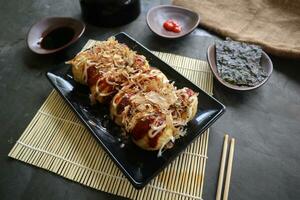 takoyaki es un japonés alimento, hecho desde trigo harina masa, pulpo carne, o otro rellenos, servido con salsa, mayonesa y Adición en el formar de katsuobushi o madera pescado virutas. foto