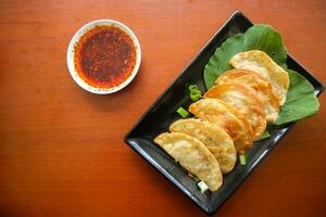 fried wonton. wonton on plate with chili oil. Shrimp or meat dumpling soup with mustard , green onions, on table photo