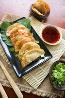 fried wonton. wonton on plate with chili oil. Shrimp or meat dumpling soup with mustard , green onions, on table photo