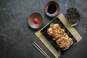Takoyaki is a Japanese food, made from wheat flour dough, octopus meat, or other fillings, served with sauce, mayonnaise and topping in the form of katsuobushi or wood fish shavings. photo