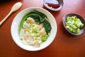 wonton soup. Bowl of wonton soup with chili oil. Shrimp or meat dumpling soup with mustard , green onions, photo