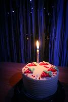 cumpleaños pastel con asperja fresa y uno velas en un azul antecedentes foto