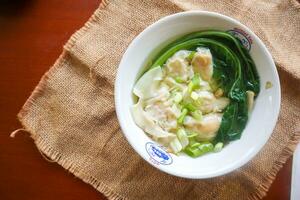 wonton soup. Bowl of wonton soup with chili oil. Shrimp or meat dumpling soup with mustard , green onions, photo