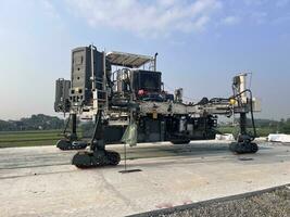 Slipform paver machine on road work at construction site. Highway concrete paving in the new quarter. Repairing concrete roads using new technology. machine photo