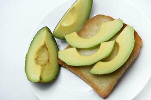 Fried toast with slices of green avocado. A delicious lunch of bread and ripe avocado. photo