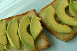 Fried toast with slices of green avocado. A delicious lunch of bread and ripe avocado. photo