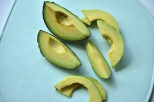 Sliced slices of green avocado in the kitchen. Delicious avocado close-up on dishes. photo