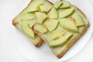 Fried toast with slices of green avocado. A delicious lunch of bread and ripe avocado. photo