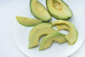 Sliced slices of green avocado in the kitchen. Delicious avocado close-up on dishes. photo