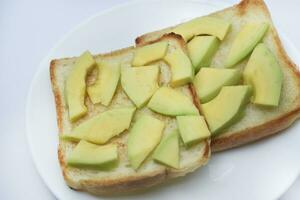 Fried toast with slices of green avocado. A delicious lunch of bread and ripe avocado. photo