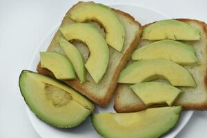 Fried toast with slices of green avocado. A delicious lunch of bread and ripe avocado. photo