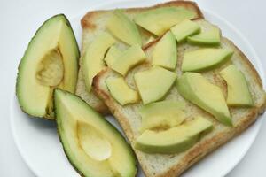 Fried toast with slices of green avocado. A delicious lunch of bread and ripe avocado. photo