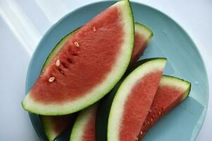 Sliced pieces of juicy red watermelon on a blue plate. Juicy fruits in summer. photo