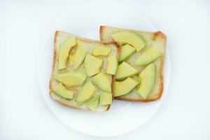 Fried toast with slices of green avocado. A delicious lunch of bread and ripe avocado. photo