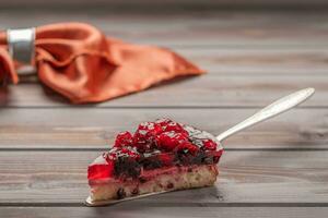 Piece of pie with berries, raspberries, currants, strawberries on the shovel on wooden background, in the background photo