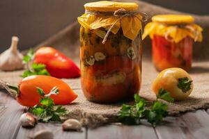 Homemade jars of pickled peppers on a rustic wooden background. Pickled and canned product. Next ingredients for cooking. photo