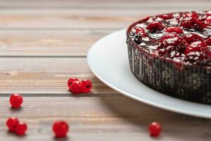 Pie with berries, raspberry, currant, strawberry on a white plate on a wooden background, near red currant photo