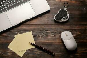 Laptop, magnifier, mouse, pen and paper for taking notes on the dark wooden table. Close up for your text photo