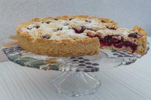 Cherry cake closeup made at home sprinkled with powdered sugar with a cut piece, visible filling photo