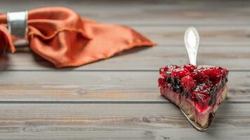 Piece of cake with berries, raspberry, currant, strawberry on a metal spatula on a wooden background, linen napkin photo