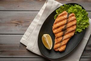Homemade grilled salmon steak on lettuce leaves. On a plate on a linen. Next to lemon. Healthy food. Top view photo