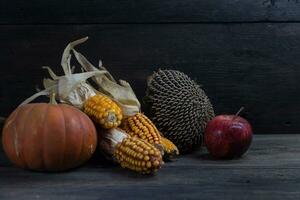 autumn harvest concept with corn squash sunflowers and apples on rustic background photo