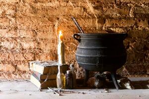 spell of witch night with candles and pot with fire between cobwebs and ancient earth photo