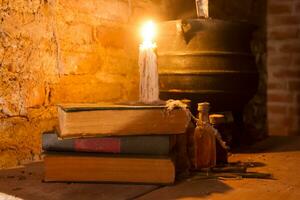 spell of witch night with candles and pot with fire between cobwebs and ancient earth photo