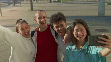 grupo de contento Adolescente amigos tomando un selfie y riendo en el ciudad calle. video