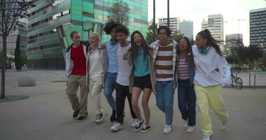 multietnisk grupp av ung Lycklig vänner gående och Hoppar ner de gata innehav varje Övrig kärleksfullt. video