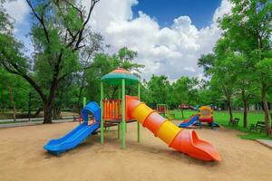 The playground in the park has big green trees. photo