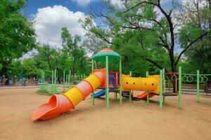 The playground in the park has big green trees. photo