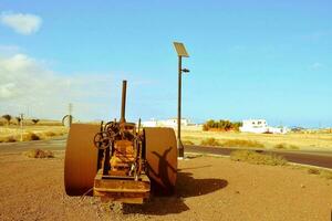 an old rusty tractor sitting on the side of the road photo