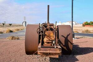 an old rusty tractor sitting on the side of the road photo