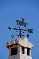 a weather vane on top of a building with a horse and rider photo