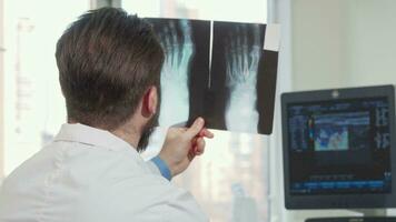 Rear view shot of a male doctor looking at foot x-ray of a patient video