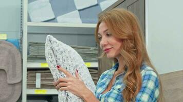 Gorgeous happy woman choosing pillows at furnishings store video