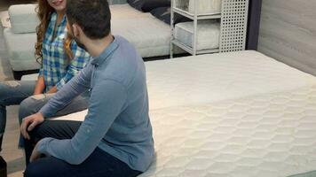 Lovely happy couple lying on comfortable othopedic mattress at furniture shop video