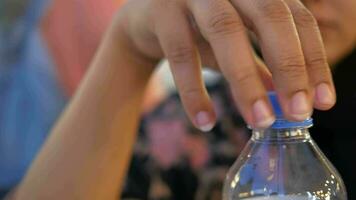 women open a cap of a plastic water bottle video