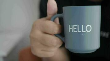 women holding a blue coffee cup with hello word video