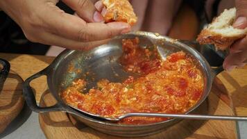 kvinnor hand äter turkiska menemen omelett i en fräsning panorera. . video