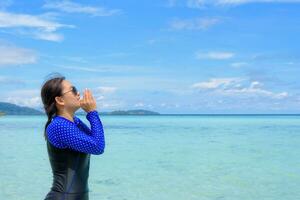 Asian woman shouting with hands on the sea in summer, Thailand photo