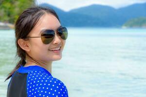 Face of a woman is smiling at the camera on the sea background photo