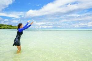 Happy asian teen girl play splashing water in the sea photo